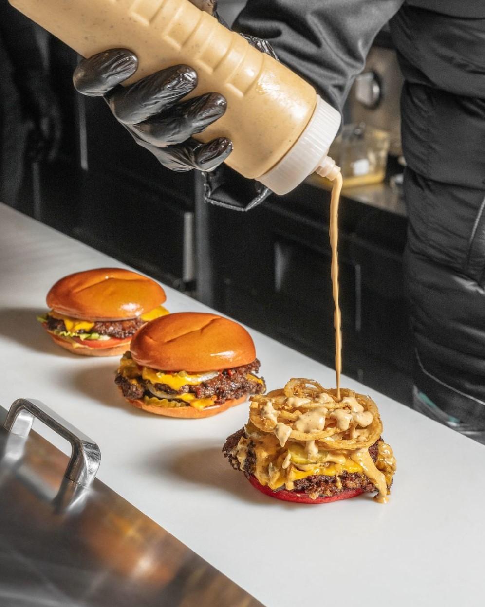 Chef finishing burgers on the kitchen pass